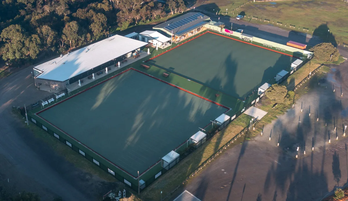 The Anglesea Bowling Club green and clubhouse from above, ringed by coastal bush