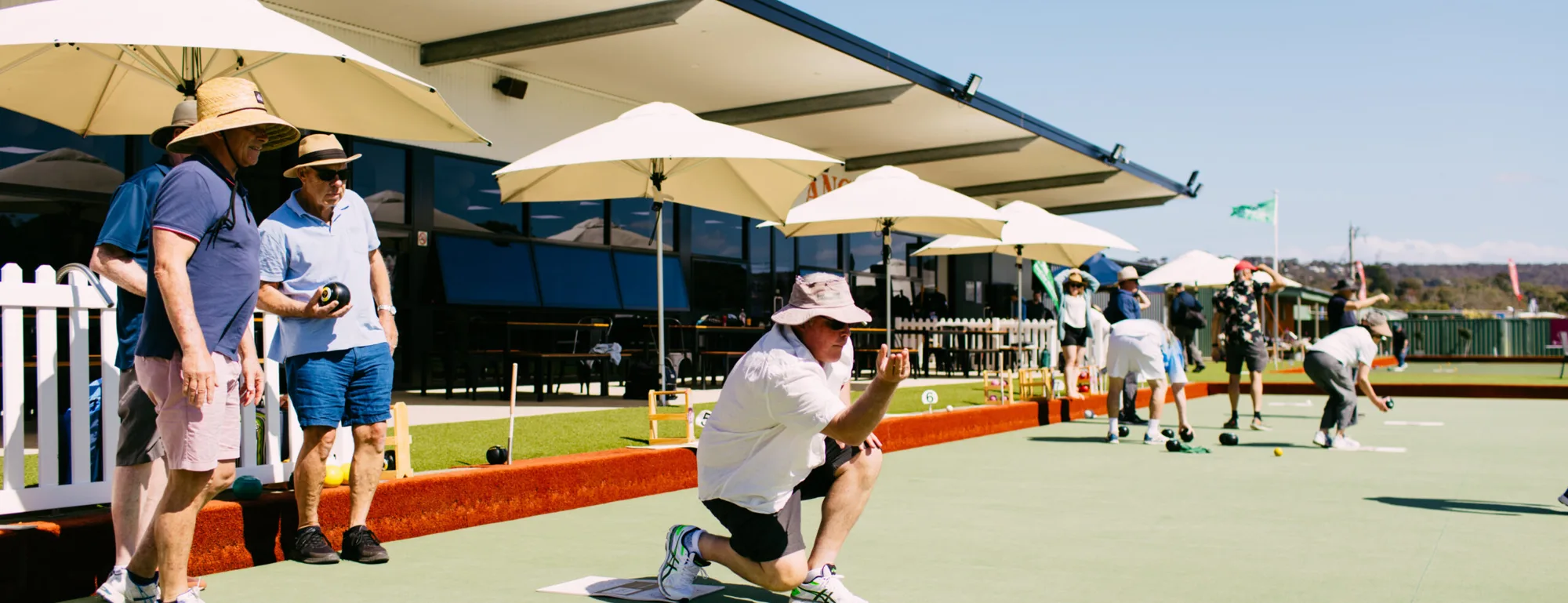 Members playing social bowls under the clubhouse umbrellas