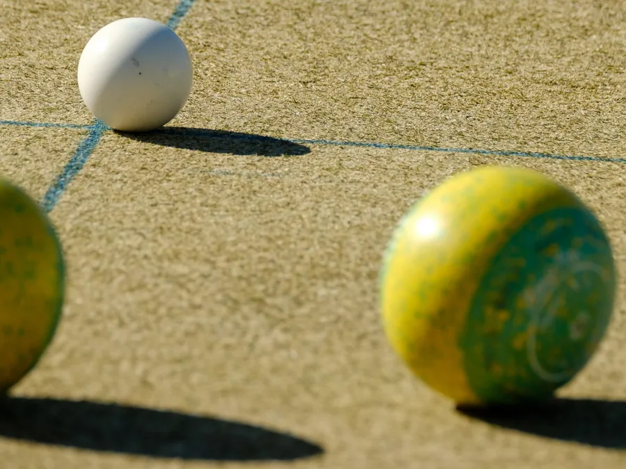 Bowls beside the jack on the green in late-afternoon sun