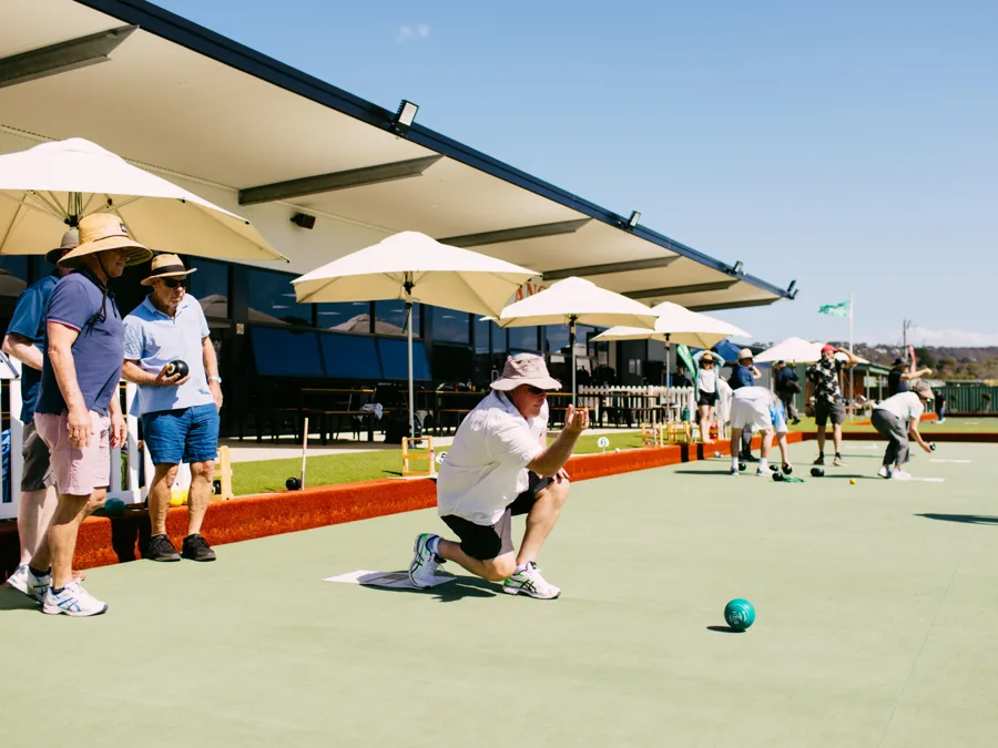 Members playing bowls under the clubhouse umbrellas